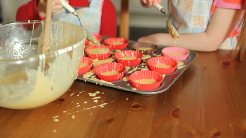 Two little girls baking and enjoying making a mess with the cake mix