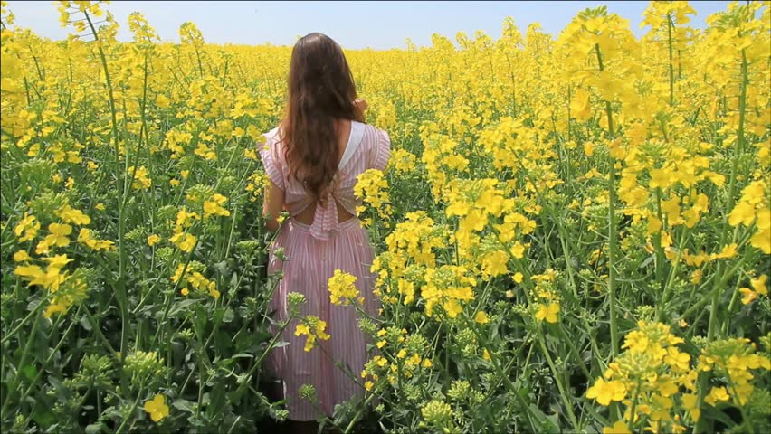 Young Woman in Vintage Dress Running through Yellow Field Touching Flowers HD