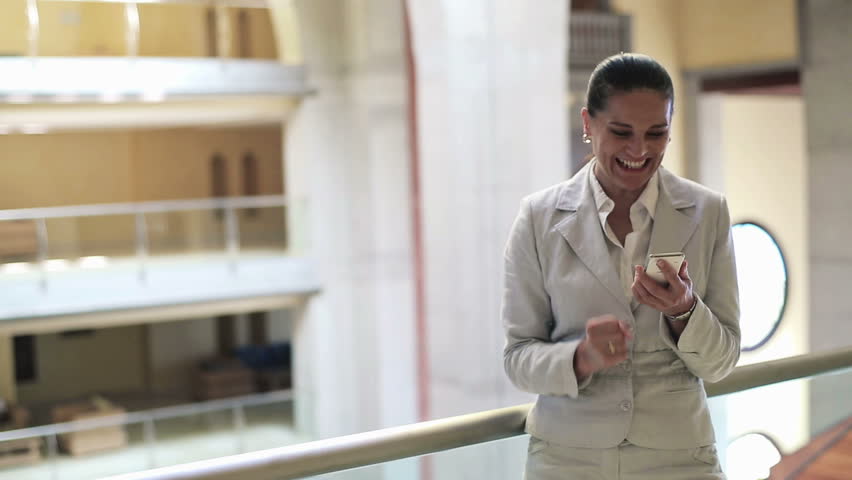 Successful businesswoman with smartphone in office building
