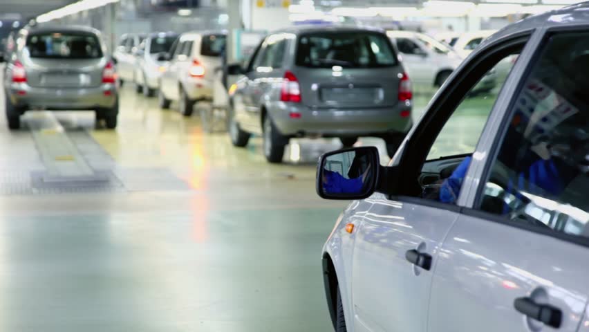 Cars comes and rides backward in hangar of factory, (unfocused)