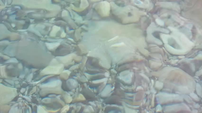 light blue water from the Mediterranean sea, with pebbles and rocks, from a beautiful beach in the island of Elba in Tuscany, Italy
