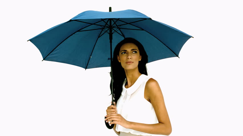 Pretty woman under blue umbrella cowering with fear on white background