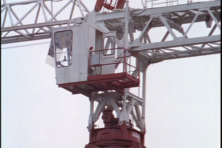 KUALA LUMPUR - OCTOBER 25, 1999: Kuala Lumpur construction site; CU top of huge white construction crane and operator compartment. Crane hook is raised up.
