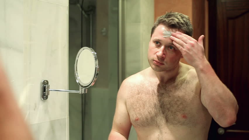 Young man applying face mask in front of mirror
