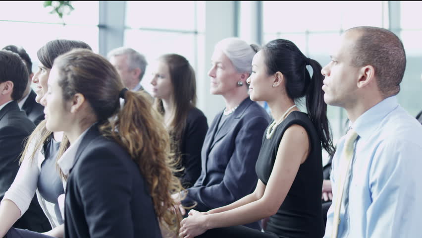 A multi ethnic group of business people of mixed ages are listening to a presentation at a business seminar and asking questions. In slow motion. 