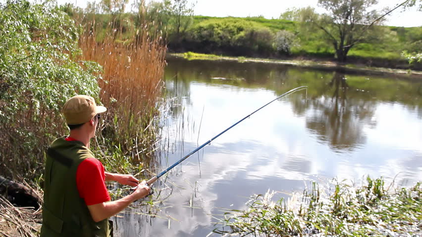 sport fisherman fishing on a river bank with fishing rod,video clip ; Fishing on the river