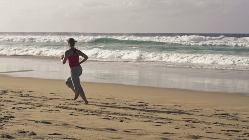 Young woman jogging on beautiful beach in the morning
