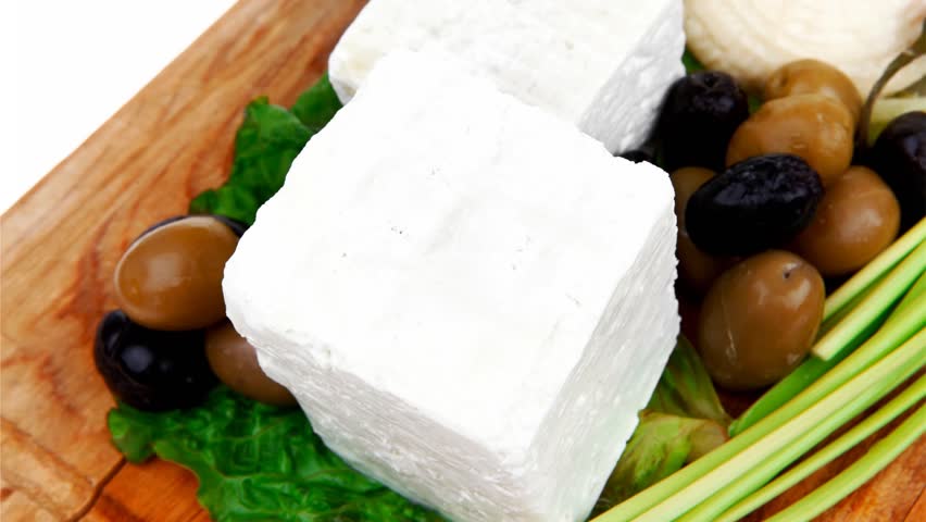 dairy food : feta white cheese cubes and round served on wooden cut plate with green leaves and olive oil 1920x1080 intro motion slow hidef hd
