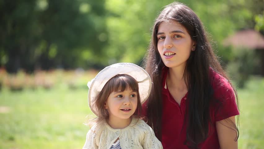 Young adult mother and daughter sing and hug together.
