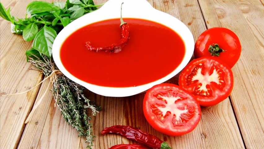 diet food : hot tomato vegetable soup with basil thyme and raw tomatoes in white round bowl over red mat on wood table ready to eat 1920x1080 intro motion slow hidef hd