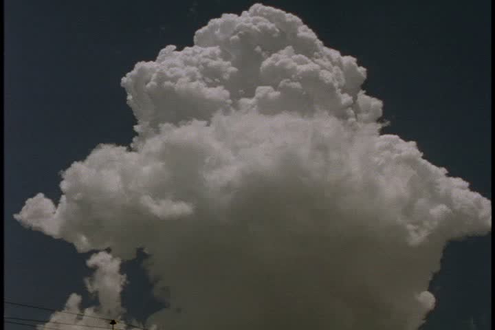 CU big fluffy white cloud expanding in slate blue sky. 