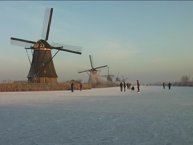 Ice skating along the windmills at the Kinderdijk in wintertime in the Netherlands