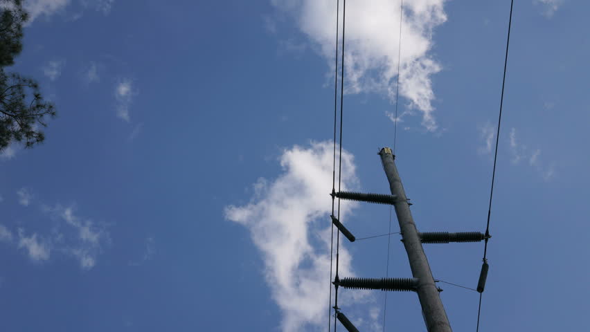 timelapse of blue sky with fluffy clouds over a high voltage powerline