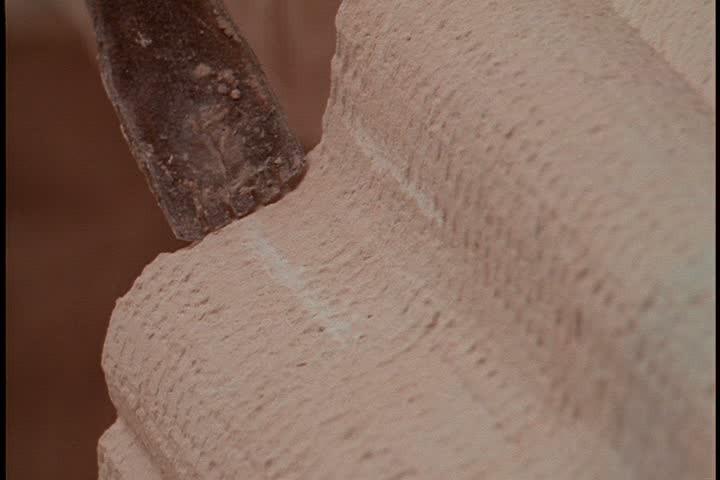 Shots of a stone carver at work; CU chisel smoothing molded column.