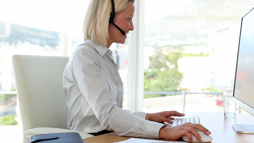 Blonde haired businesswoman working with a headset in her office