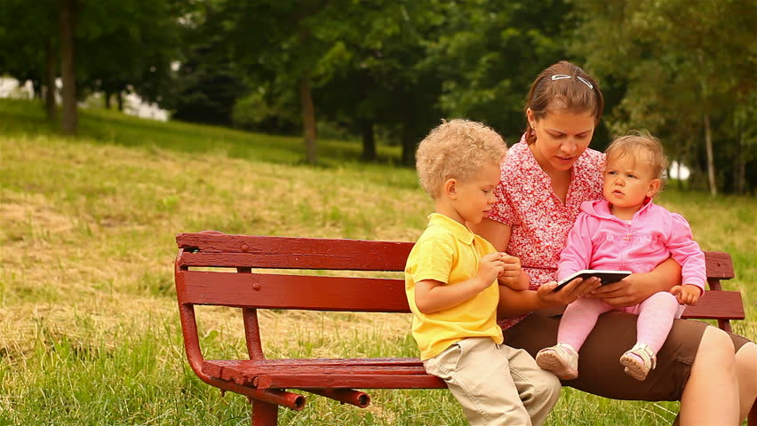 mother and two children, reading and watching Tablet Computers