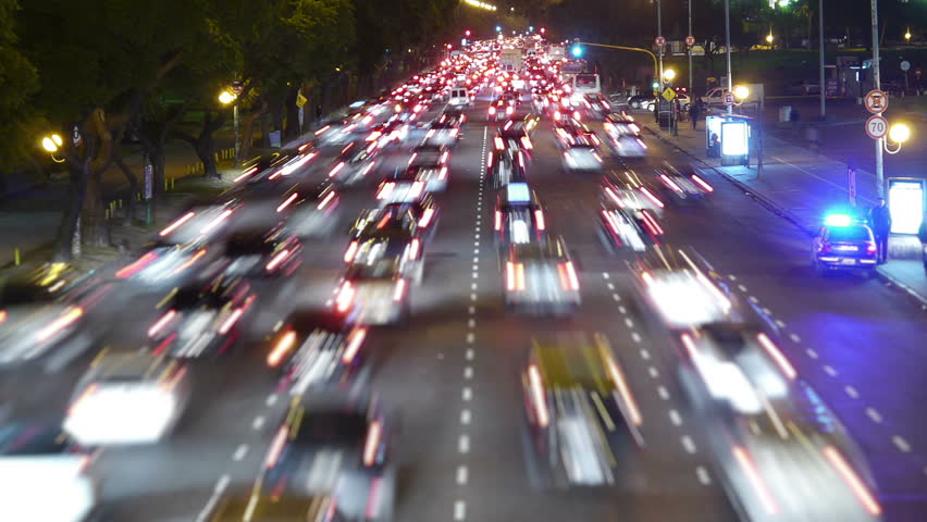 Traffic in the city. Avenue Time-Lapse, Night. Moon going down. Heavy traffic / jam / flowing with blurred motion. Dusk. Crane up / zoom.
