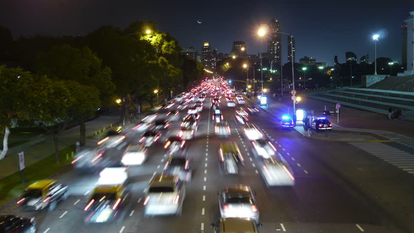 Traffic in the city. Avenue Time-Lapse, Night. Moon going down. Heavy traffic / jam / flowing with blurred motion. Dusk. Dolly in / zoom.