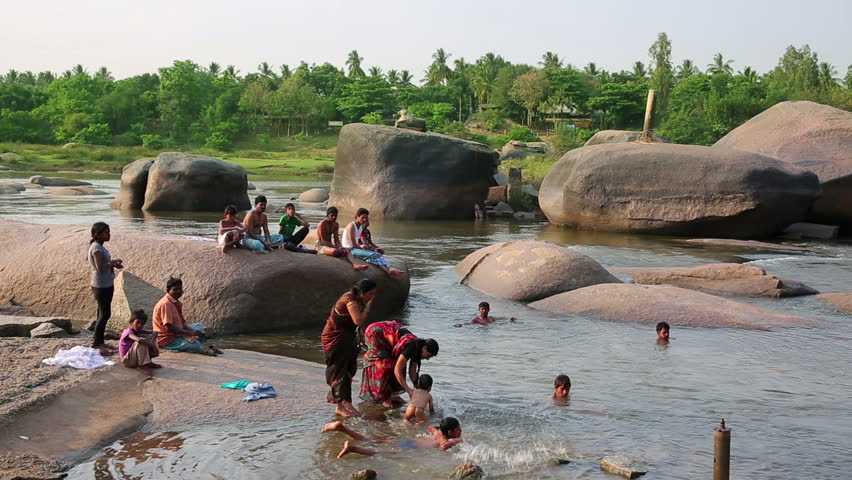 HAMPI, KARNATAKA, INDIA - APRIL 2013: People bathing in mountain river