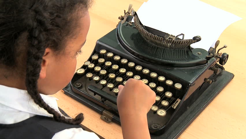 Cute african american schoolgirl using an old fashioned typewriter