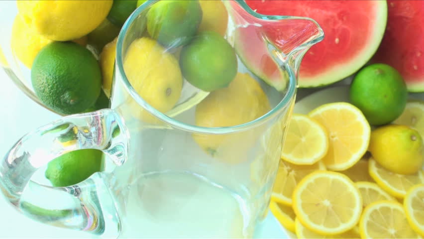 1920x1080 Lemonade poured into pitcher against background of sliced limes, watermelon and lemons.