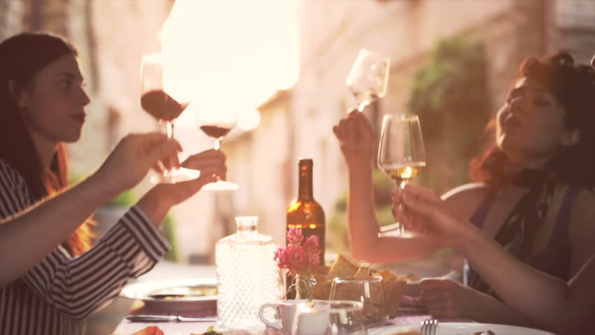 Friends raising wine glasses to make a toast and drinking wine, Slow motion