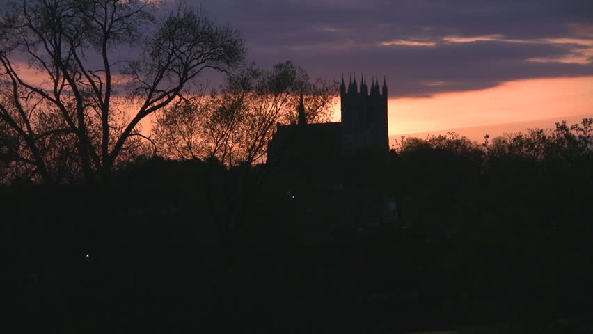 The 'Church of our lady' in Guelph, Ontario, Canada, shot as the sun sets, with a glow of oranges, purples and pinks, outlining its shape.