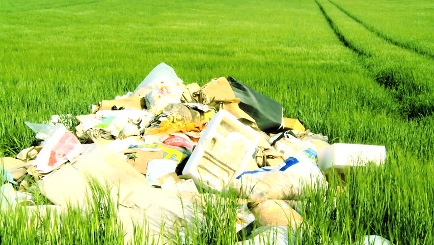 Concept shot of discarded rubbish (trash) polluting a clean environmental field