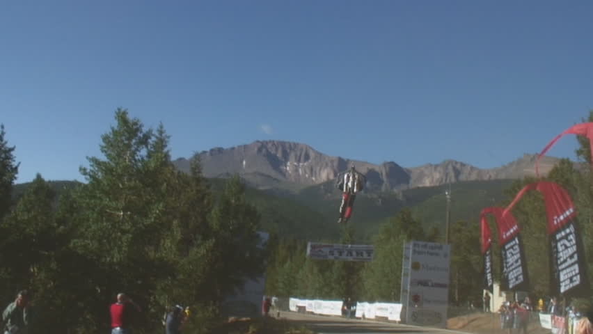 Pilot Eric Scott prepares his Jet Pack for flight, lifts off and rockets away with mountains in background