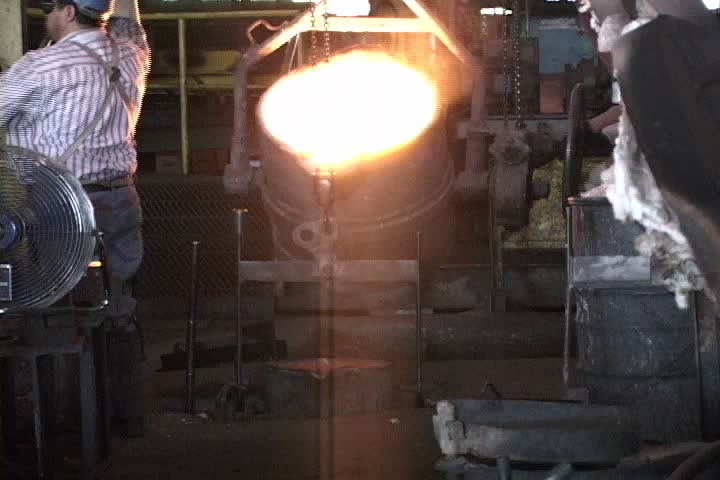 Molten iron being poured into a smaller bucket for casting