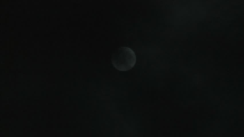 moon in the night sky hides behind quickly running clouds  