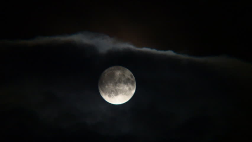Time lapse of full moon emerging from behind night clouds.