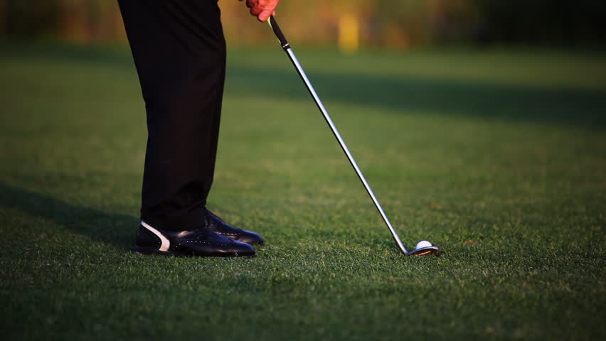 Close up of golf ball sitting on tee with driver swings and hits the ball