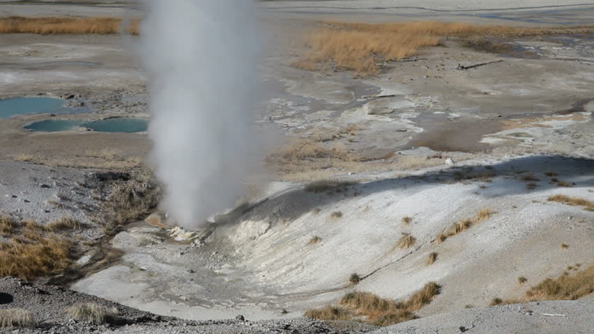 Clear water geyser in the Norris Geyser Basin, Porcelain Basin, Yellowstone National park, Wyoming. Continuous steam blowing from ground. Hot steam geothermal feature.