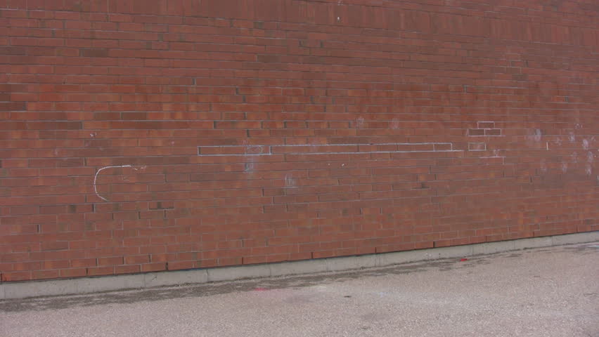 A pan across a red brick public school, showing a rear entrance, and a concrete courtyard.