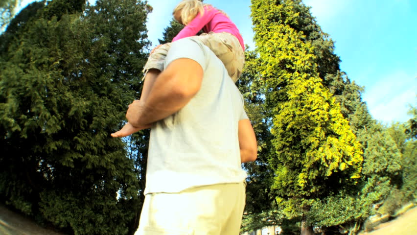 Young father  holding his daughter while outdoors on a summers day