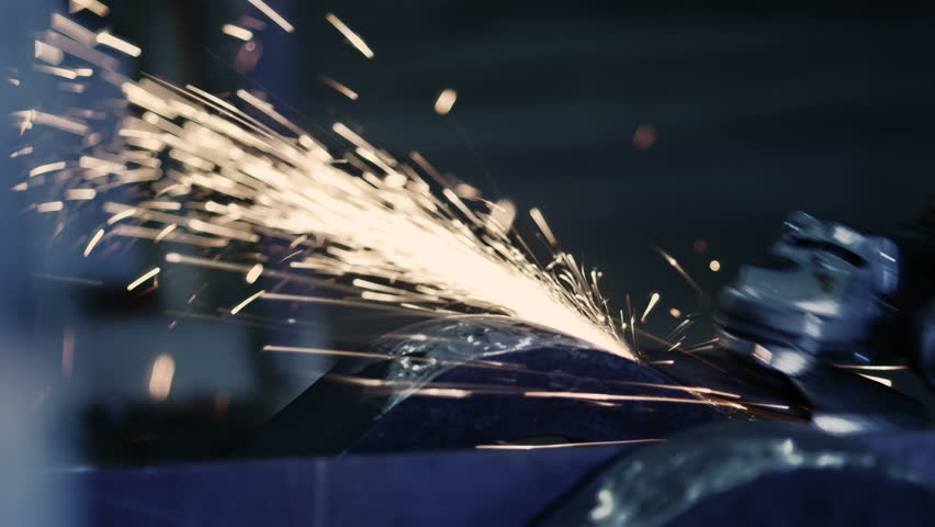 Close-Up of Grinding Heavy Industry Worker. Wearing Hardhat and Protective Headphones. Sparks on Background. Shot on RED Digital Cinema Camera in 4K, ultra-high definition, UHD
