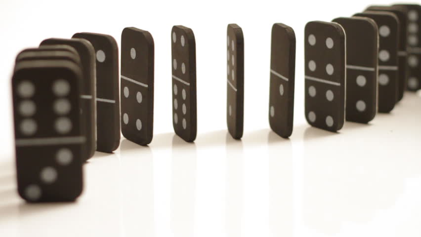 A curved set of black dominoes isolated on white, falling over, starting at the back and falling forward.