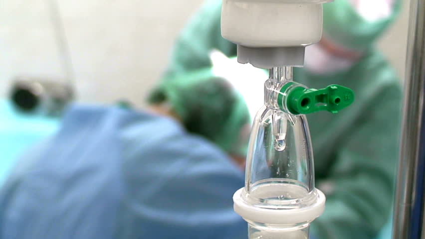 intravenous drip in operation room with surgeons on background