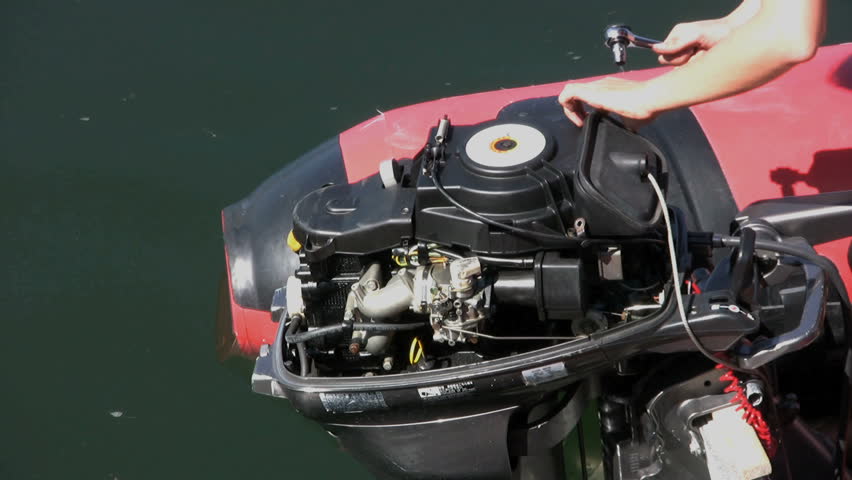 A woman using a ratchet wrench trying to fix an outboard motor.