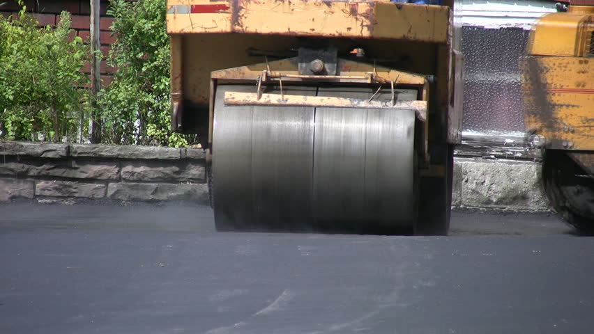 Steamroller flattens asphalt.  Yellow steamroller smoothing hot asphalt. 