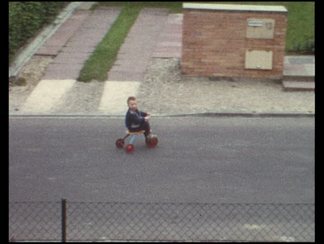 Boy riding trike on street (vintage 8 mm amateur film)