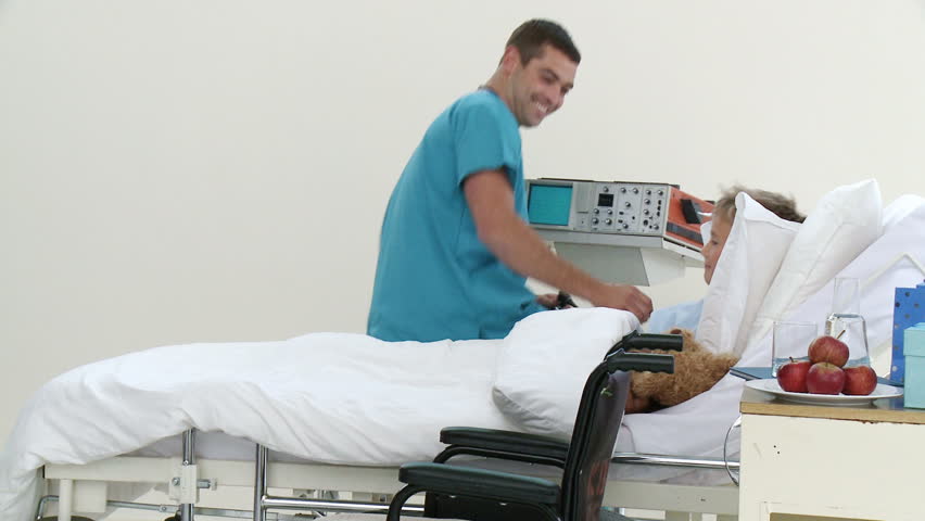 Panorama of male doctor playing with a little patient recovering in hospital and his teddy bear