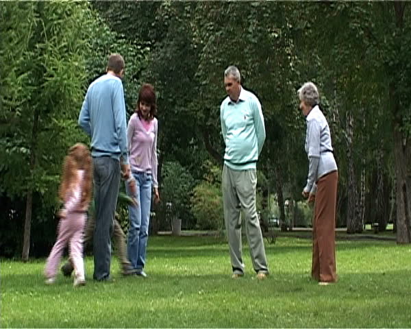 Children running near their parents and grandparents while spending time outdoors together