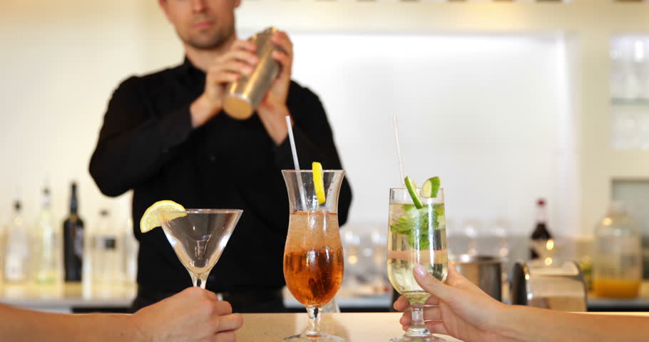 Friends watching bartender shake and serve cocktail at the local bar