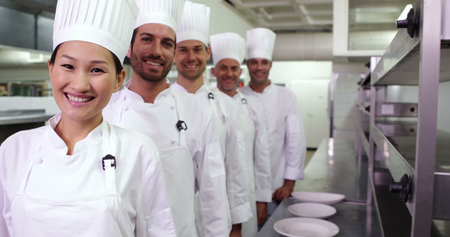 Smiling chefs standing in a line in a commercial kitchen