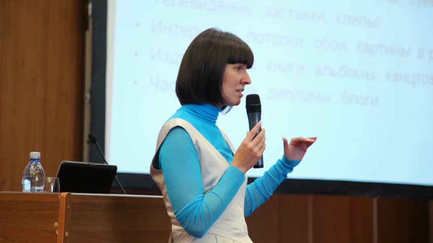 woman speaking through a microphone in conference hall 