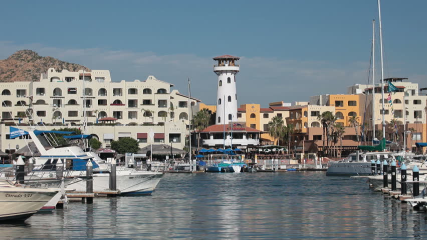 Cabo San Lucas marine harbor with boats, fast motion. Mexican resort and cruise port. Lighthouse and docks. Sailboats, power boats and water taxi. Tourist dock area in Mexico.