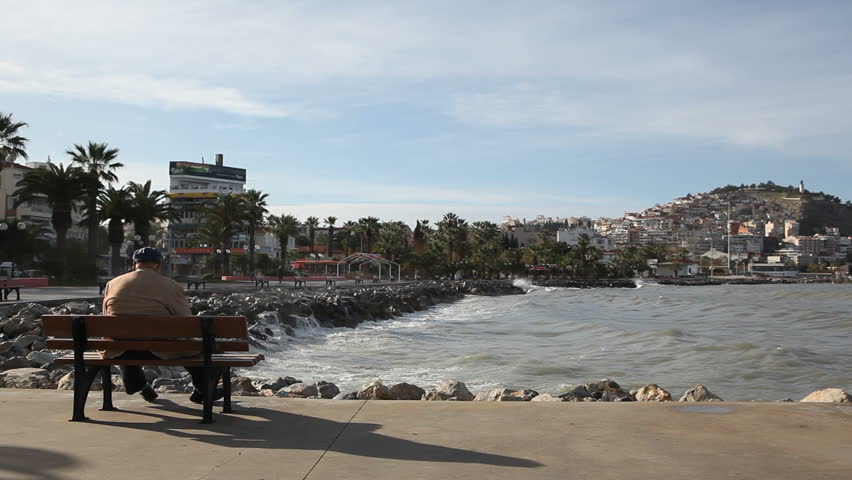 KUSADASI, TURKEY - 19 DECEMBER: Man watches large waves in the Harbor of Kusadasi. A night of severe storms knocked out power grids, and caused major water damage to vehicles and property.
