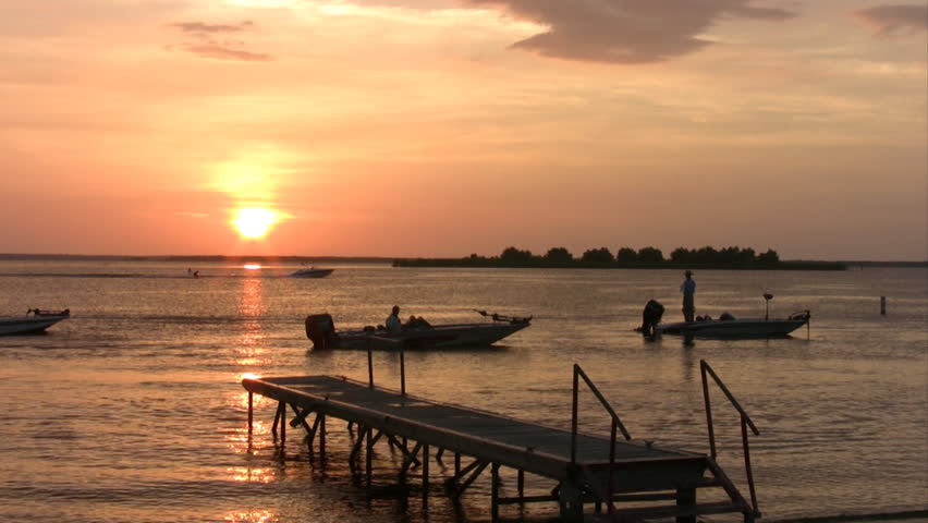 Video of a fishing boat at Chock Canyon Lake in south Texas.  Vivid bright orange sunset. around boat dock and ramp. 